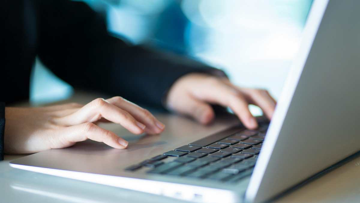 Hands typing on a laptop keyboard