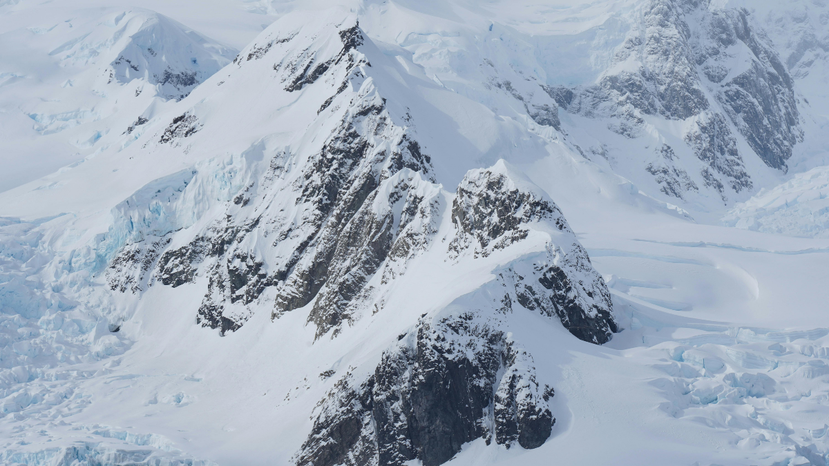Snow-covered mountain peaks with steep rock faces and glaciers in the background